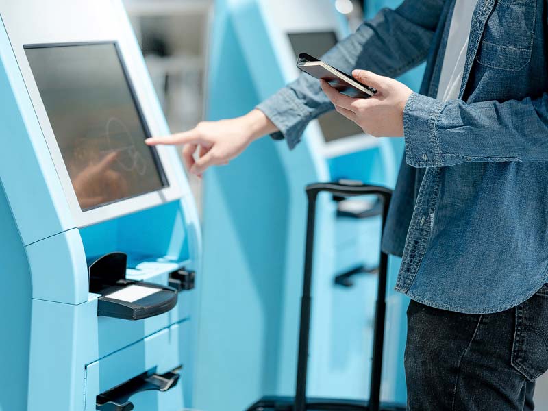 persona interactuando con maquina de auto ayuda en un aeropuerto